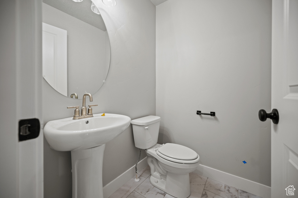 Half bath featuring baseboards and marble look tile flooring