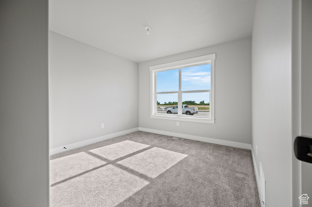 Carpeted spare room featuring baseboards