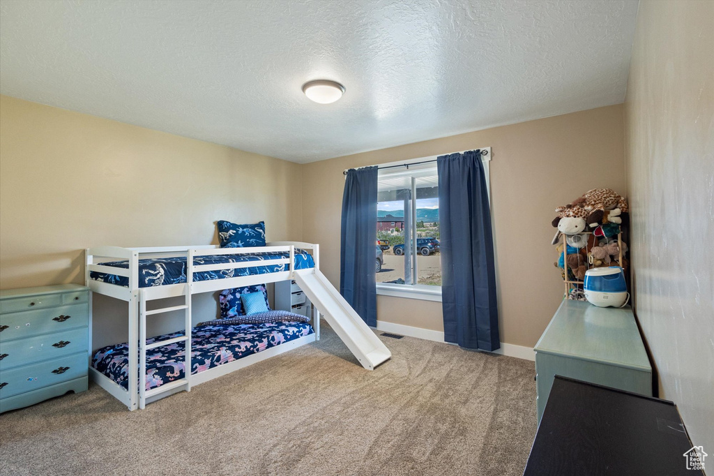 Carpeted bedroom featuring a textured ceiling and baseboards