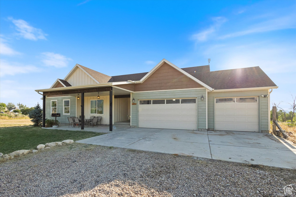 View of front facade with an attached garage, concrete driveway, board and batten siding, and a front yard