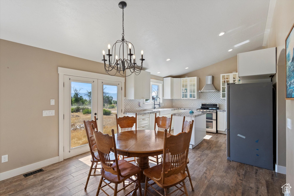 Dining space with lofted ceiling, dark wood-style flooring, a chandelier, recessed lighting, and french doors