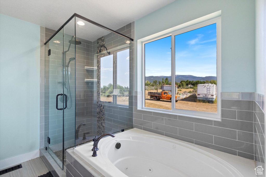 Bathroom featuring a mountain view, a tub with jets, a shower stall, and recessed lighting