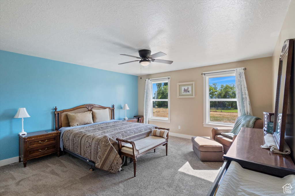 Carpeted bedroom featuring a textured ceiling and ceiling fan