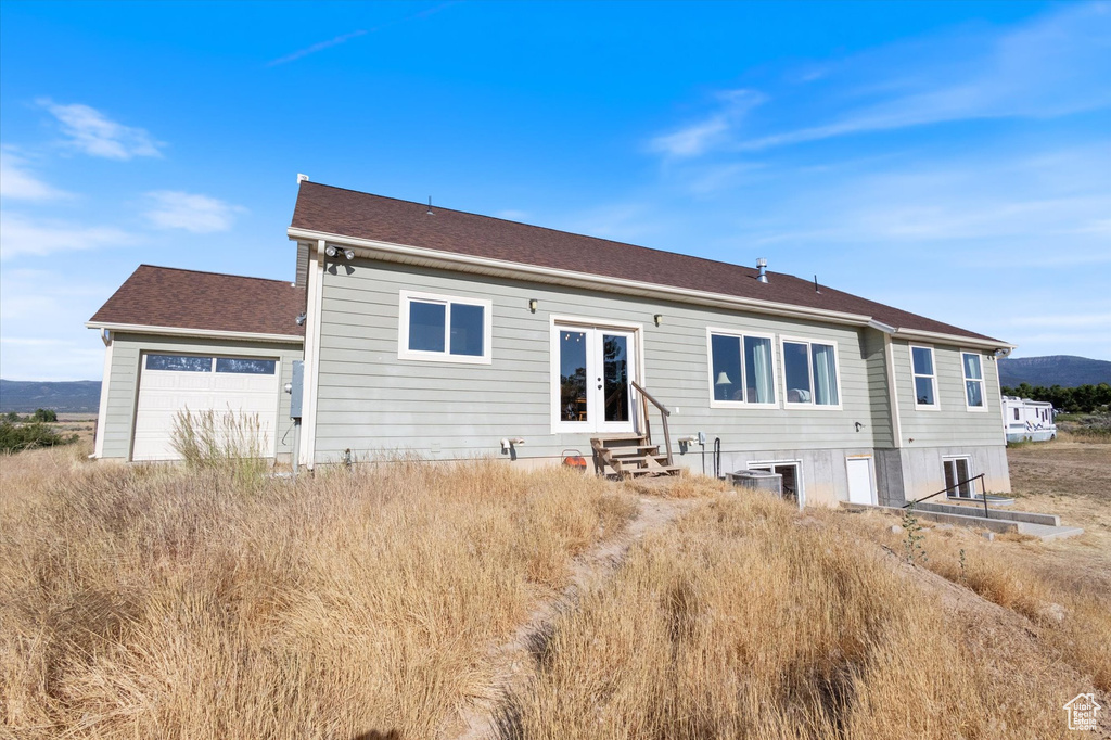 Back of house featuring french doors, entry steps, a garage, a mountain view, and a shingled roof