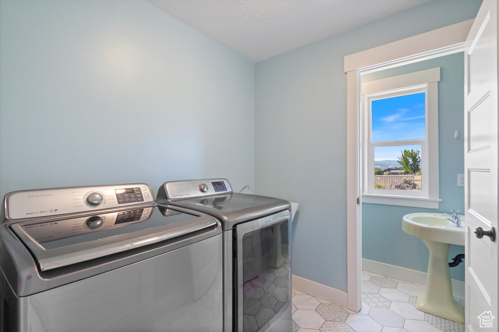 Washroom with washer and clothes dryer and light tile patterned flooring