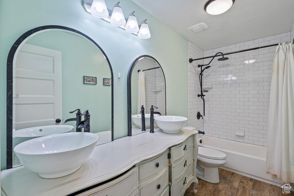 Bathroom with wood finished floors, vanity, and shower / tub combo with curtain