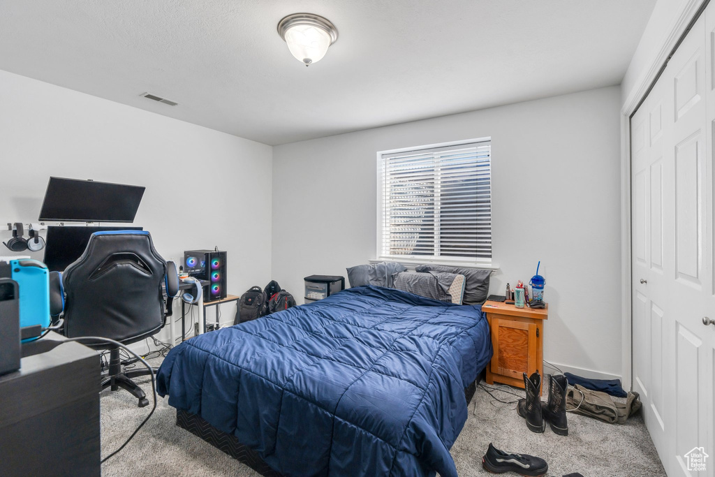 Carpeted bedroom featuring a closet and a desk