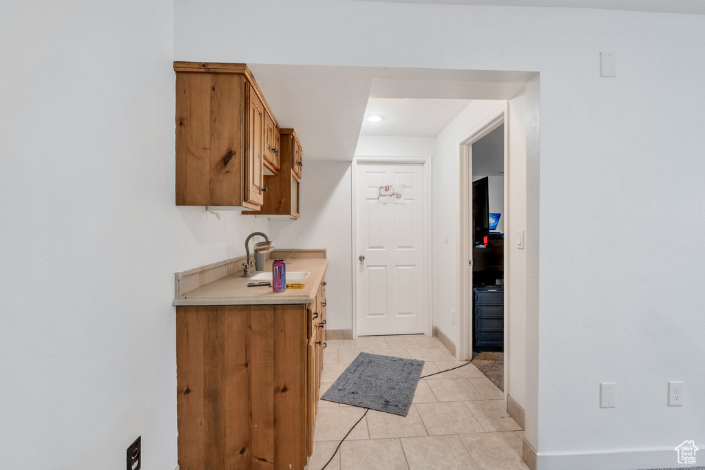 Kitchen featuring brown cabinetry, light countertops, light tile patterned floors, and recessed lighting
