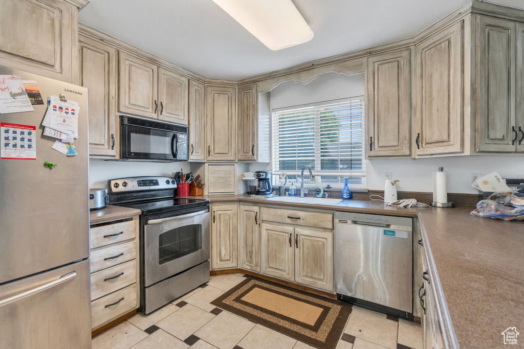 Kitchen featuring appliances with stainless steel finishes, dark countertops, and cream cabinetry