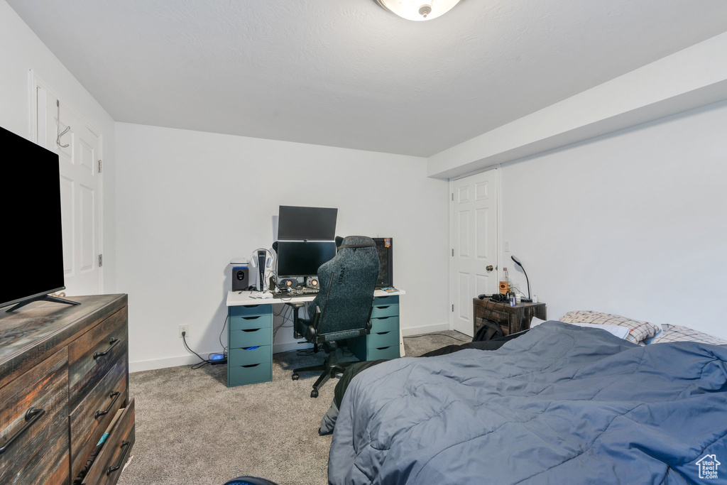 Carpeted bedroom with baseboards and an office area