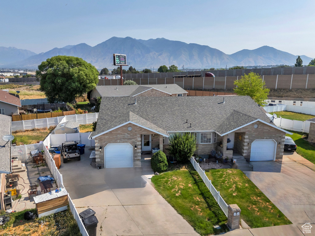View of front of home with concrete driveway, an attached garage, stone siding, a mountain view, and a shingled roof