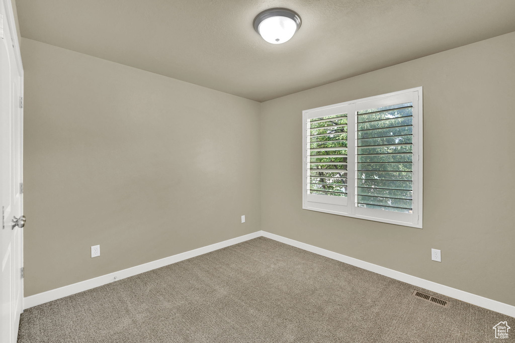Carpeted spare room featuring baseboards