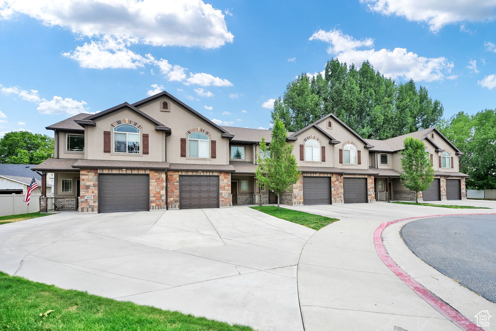 Multi unit property featuring stucco siding, an attached garage, and stone siding