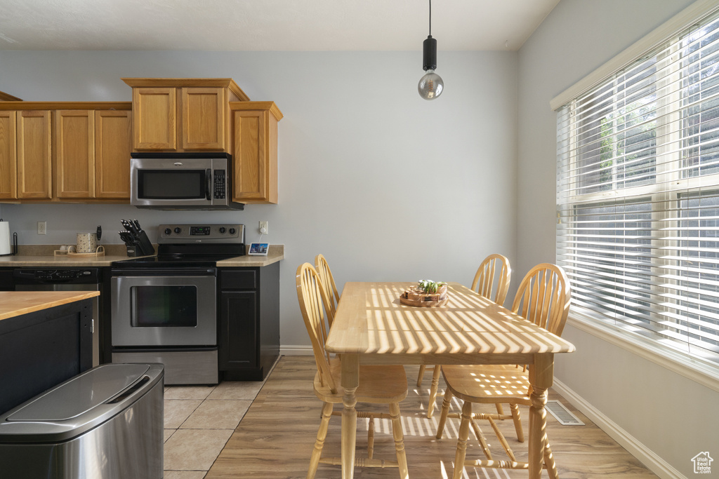 Kitchen featuring appliances with stainless steel finishes, light countertops, light tile patterned floors, and pendant lighting