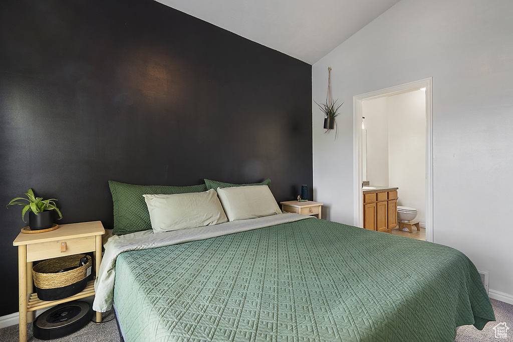 Carpeted bedroom with lofted ceiling and connected bathroom