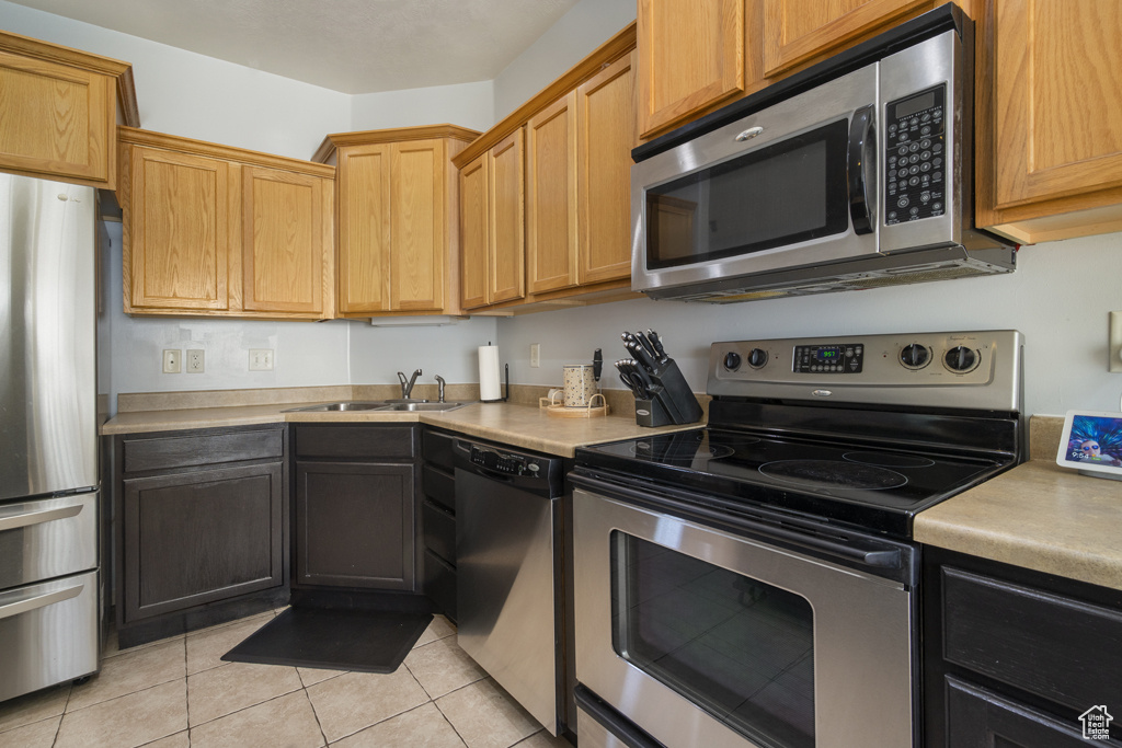 Kitchen with appliances with stainless steel finishes, light countertops, and light tile patterned floors