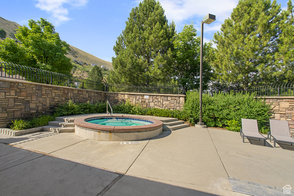 View of swimming pool with a community hot tub, a mountain view, and a patio area
