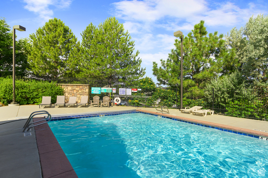 Community pool with a patio and view of scattered trees