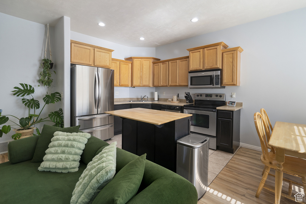 Kitchen with appliances with stainless steel finishes, butcher block counters, a kitchen island, recessed lighting, and light wood-type flooring
