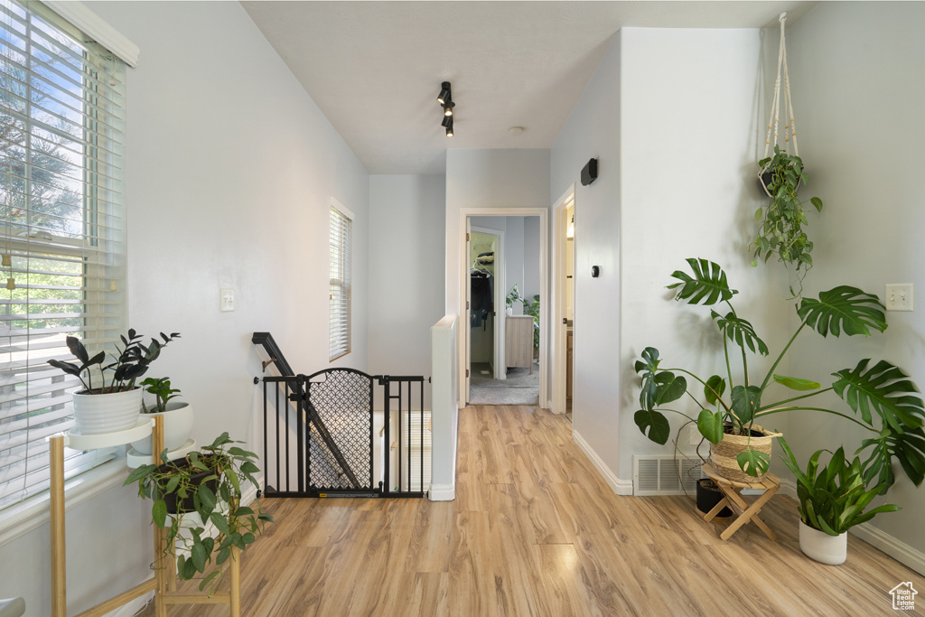 Corridor featuring an upstairs landing and light wood finished floors