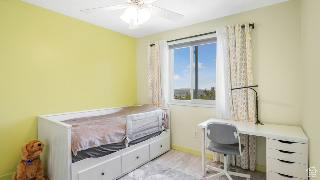 Bedroom with wood finished floors, an office area, and ceiling fan