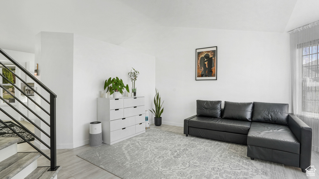 Living room featuring wood finished floors, stairs, and lofted ceiling