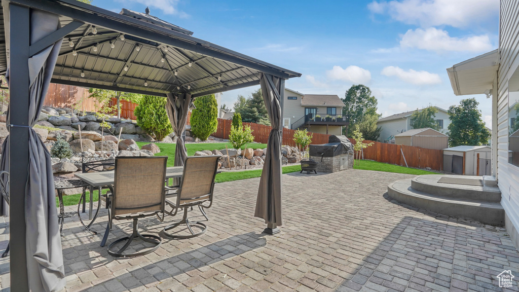 Fenced backyard with a patio, a storage unit, outdoor dining area, and a gazebo