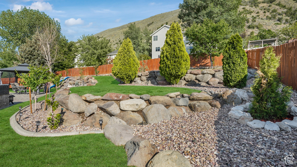 Fenced backyard featuring a mountain view, a patio area, and a gazebo