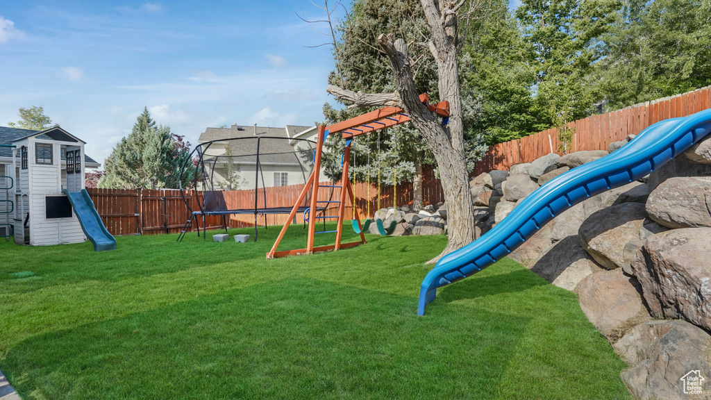 View of jungle gym featuring a trampoline and a fenced backyard