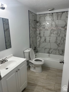 Bathroom with vanity, shower / bath combination, and a textured ceiling