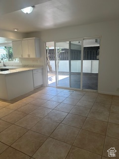 Kitchen with white cabinets, tile patterned flooring, light countertops, and a peninsula