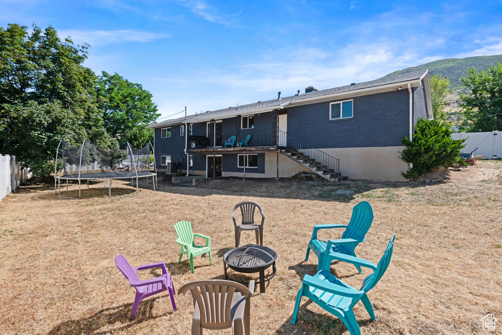 Rear view of property featuring a fire pit, a trampoline, stairs, and brick siding