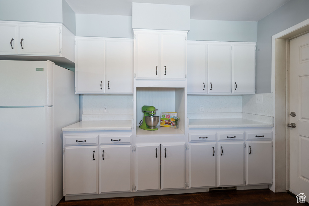 Kitchen with freestanding refrigerator, light countertops, white cabinetry, and dark wood finished floors