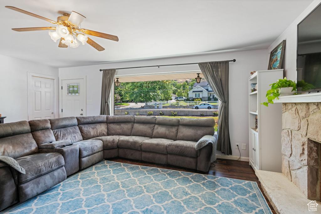 Living room with wood finished floors, ceiling fan, and a fireplace