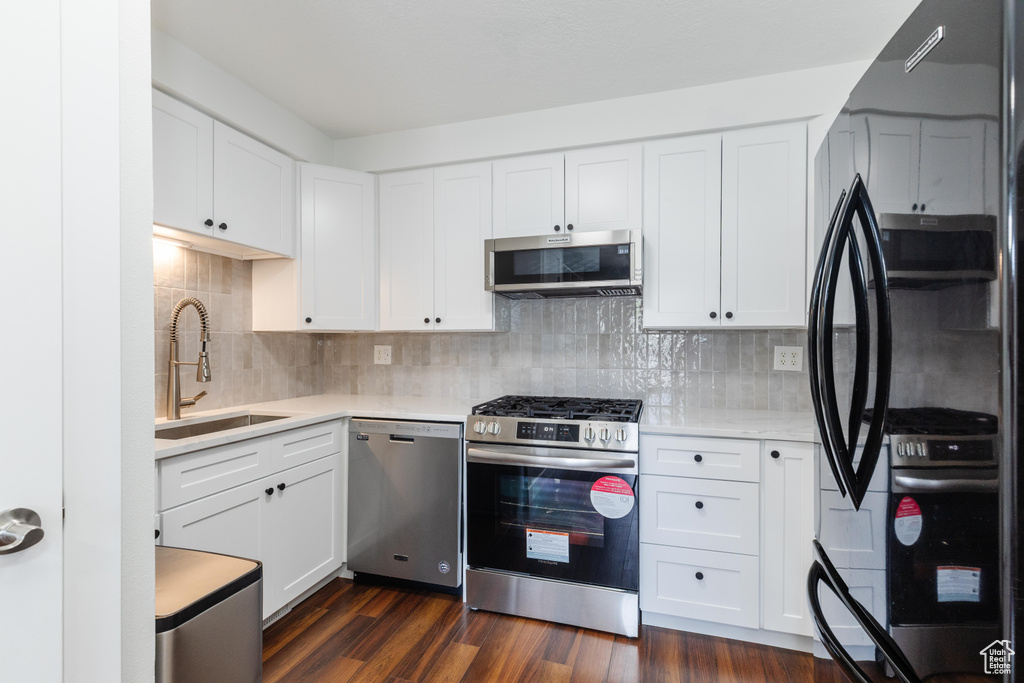 Kitchen with appliances with stainless steel finishes, light countertops, decorative backsplash, and white cabinetry
