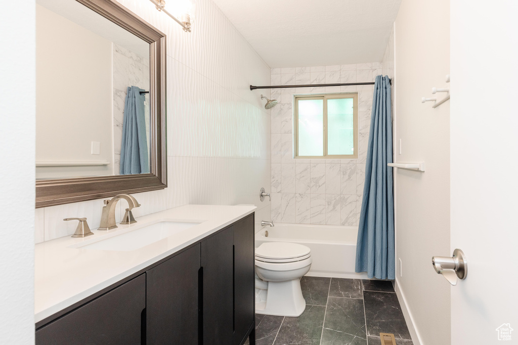 Bathroom with vanity, shower / tub combo with curtain, and marble look tile flooring