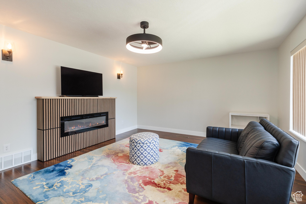 Living room with a glass covered fireplace and dark wood-style flooring