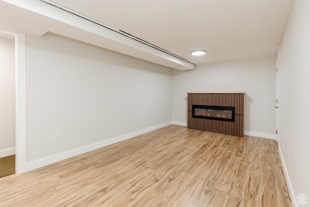 Unfurnished living room with wood finished floors and a glass covered fireplace