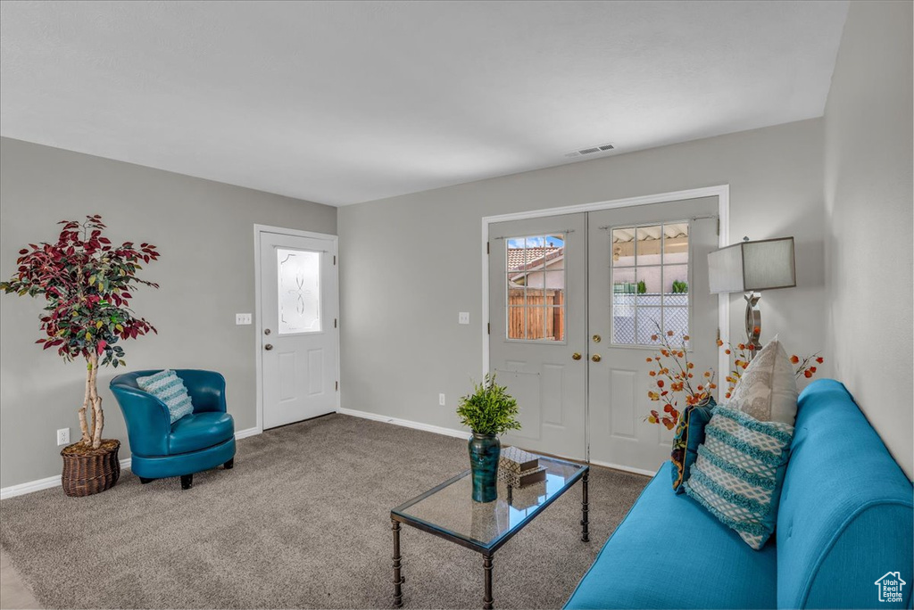 Carpeted living room with french doors and baseboards