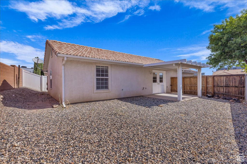 Back of property featuring stucco siding, a patio area, a tiled roof, and a fenced backyard