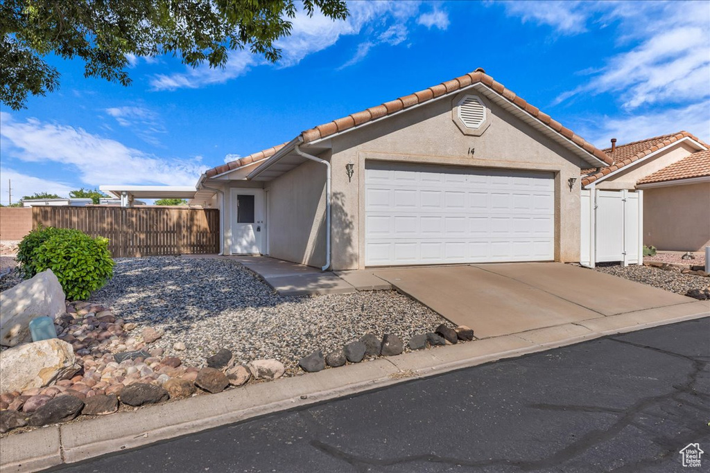 Ranch-style home with a tiled roof, concrete driveway, a garage, and stucco siding