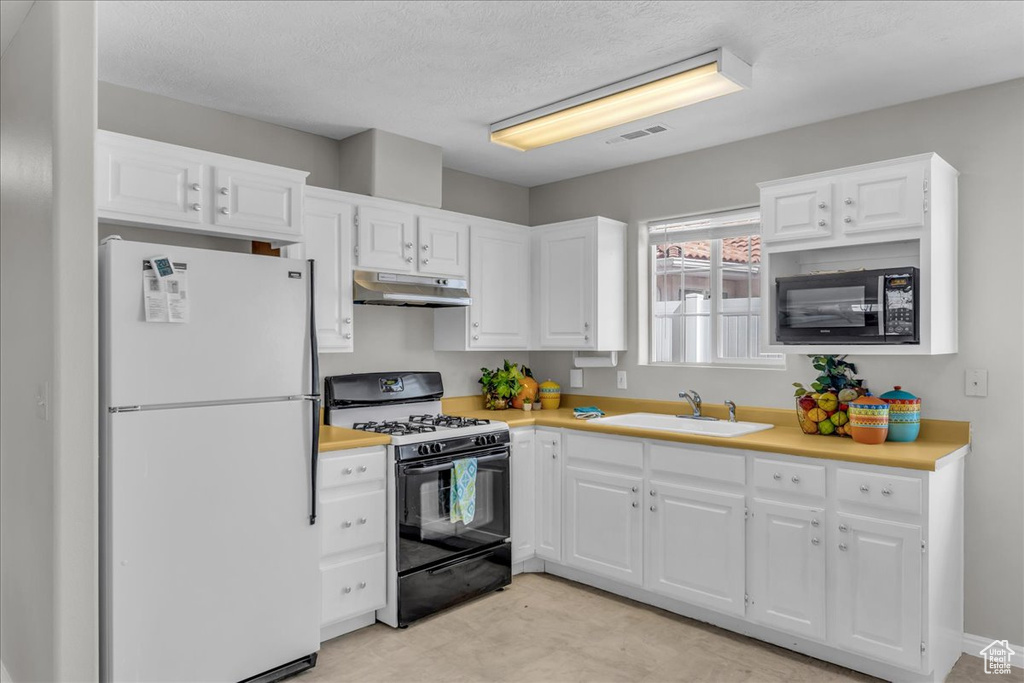 Kitchen featuring black appliances, under cabinet range hood, light countertops, white cabinets, and a textured ceiling