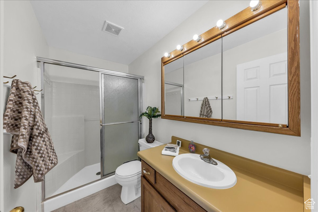 Bathroom with vanity, a shower stall, and tile patterned flooring