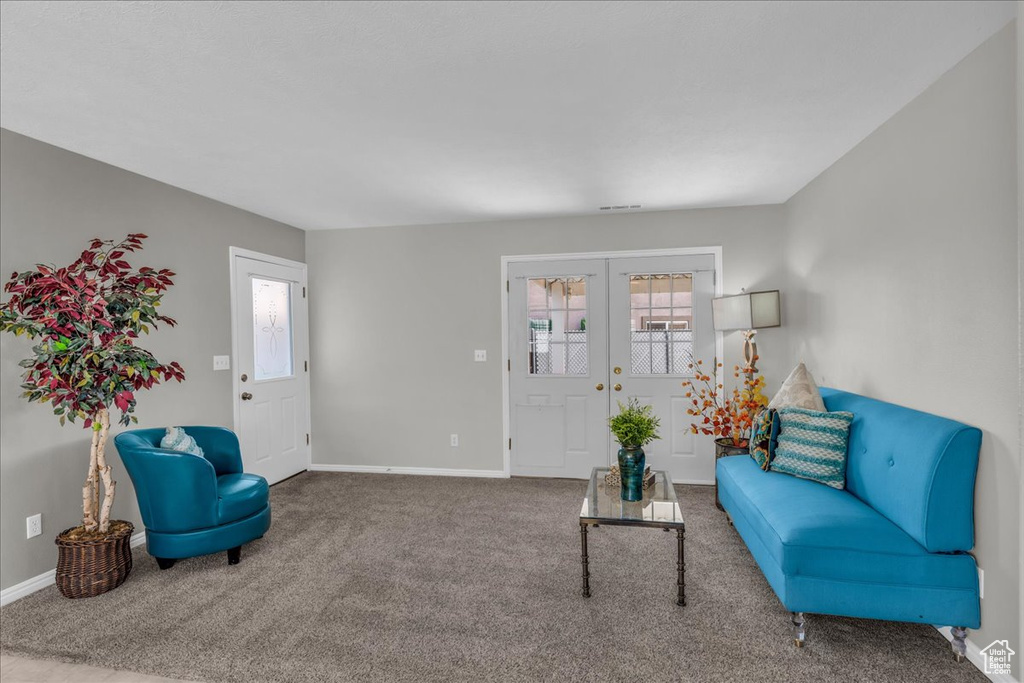 Carpeted living area with french doors and plenty of natural light