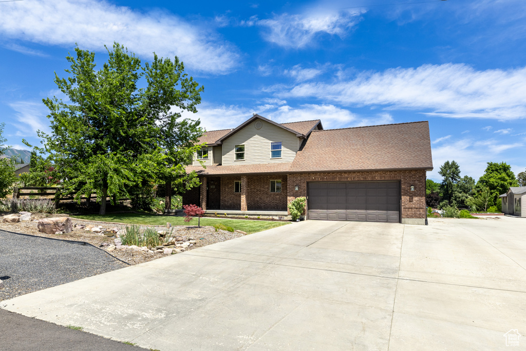 View of front of house featuring brick siding, concrete driveway, an attached garage, and roof with shingles