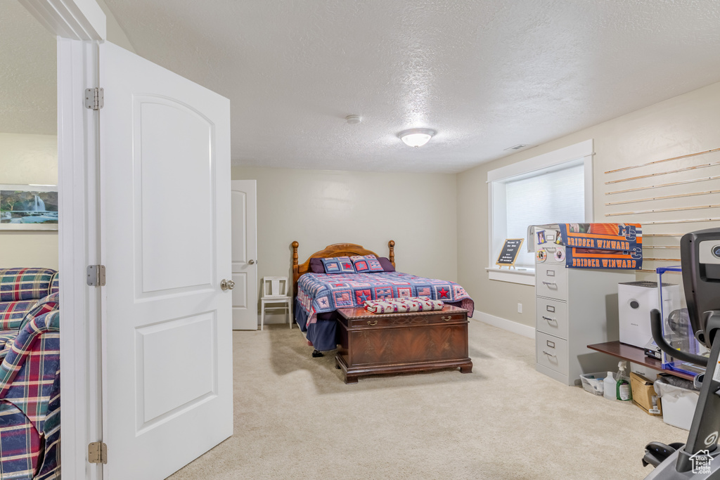 Bedroom featuring light colored carpet and a textured ceiling