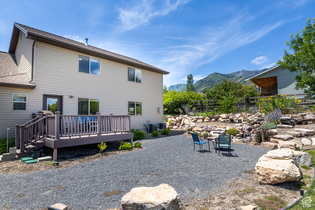 Back of property featuring a deck with mountain view and roof with shingles