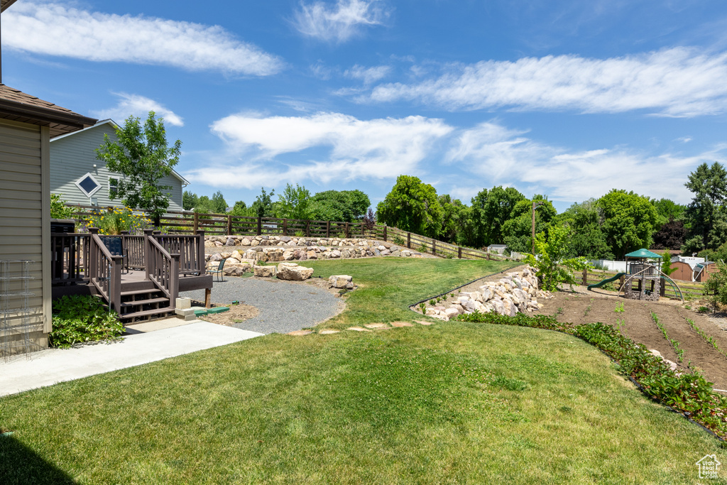 View of yard with a playground and a wooden deck