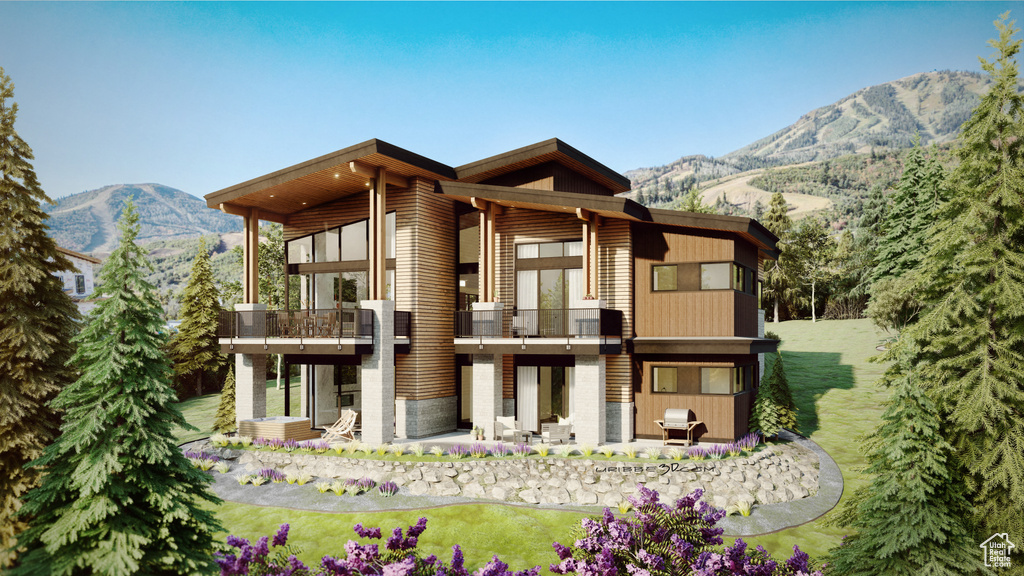Back of property with a balcony, a mountain view, a patio, and a yard