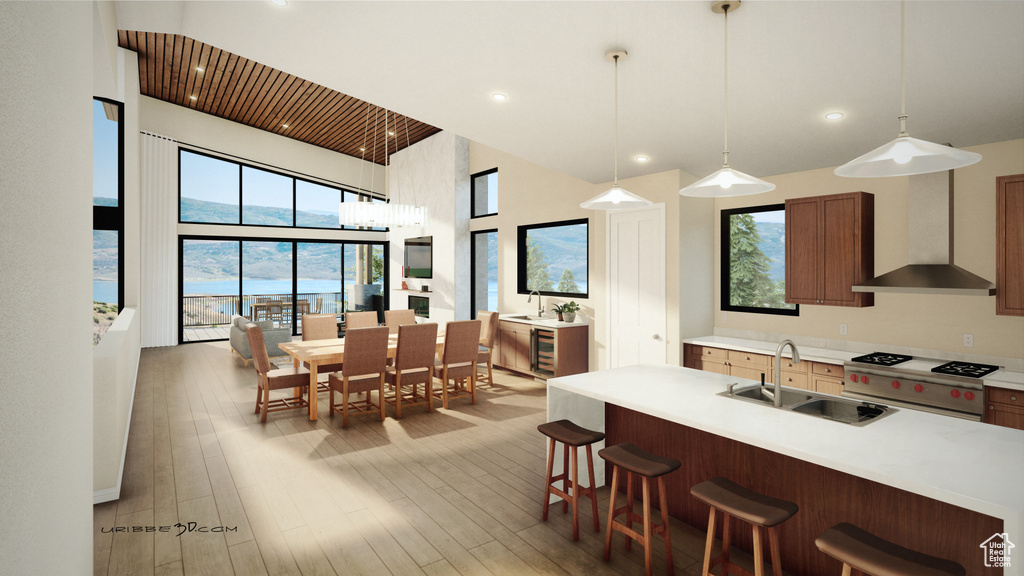 Kitchen featuring premium range, wall chimney range hood, light countertops, light wood finished floors, and a high ceiling